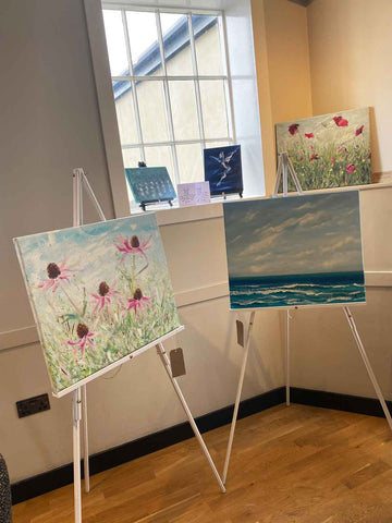 Art display with flower, seascape and dance paintings of various sizes