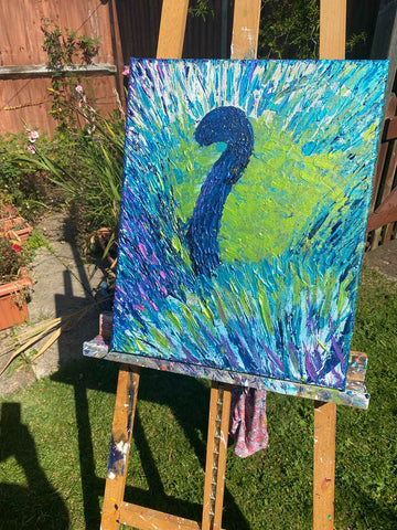 Peacock painting in progress on easel in garden