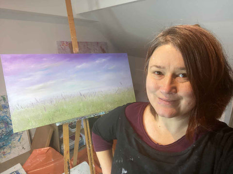 Art studio selfie of woman in front of painting on easel