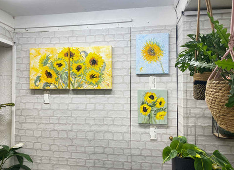 3 sunflower paintings on wall in interor with plants