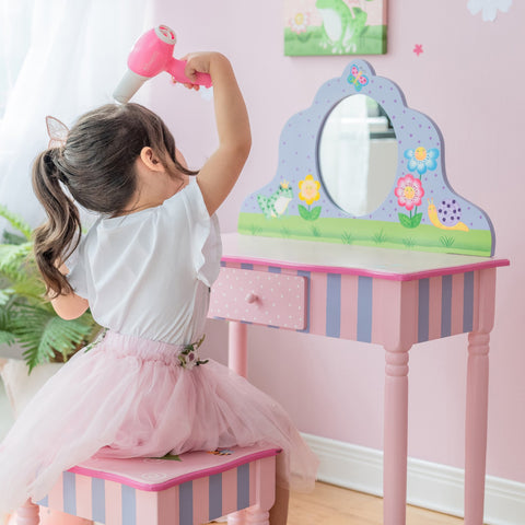 Little girl pretending to blow dry her hair in front of her pink vanity with matching stool