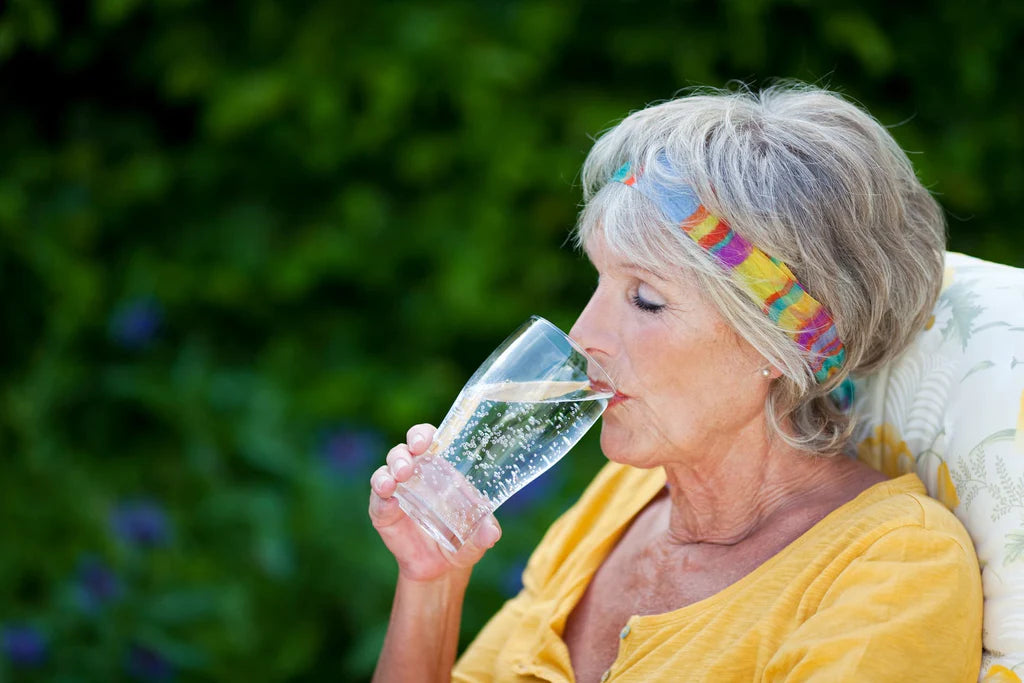 old woman drinking a glass of sparkling water