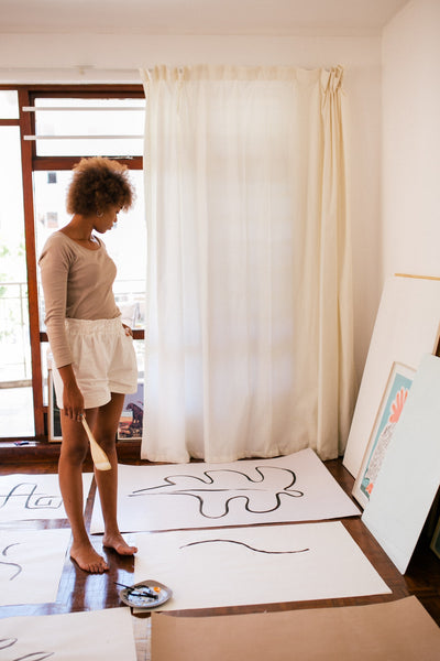 Female artist standing in a room looking at paintings.