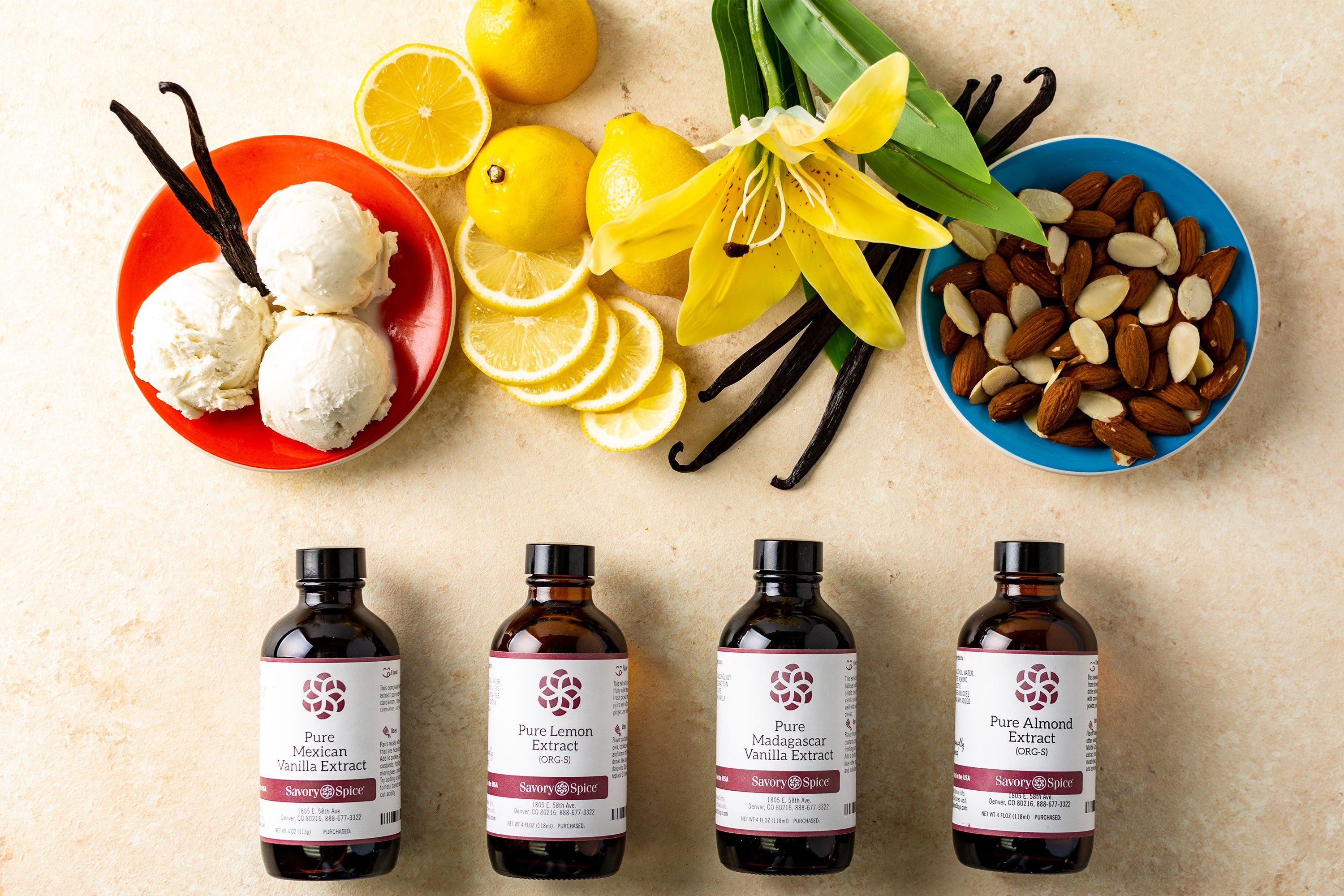 Four different extract bottles with ice cream, lemons, orchid, vanilla beans, and nuts above