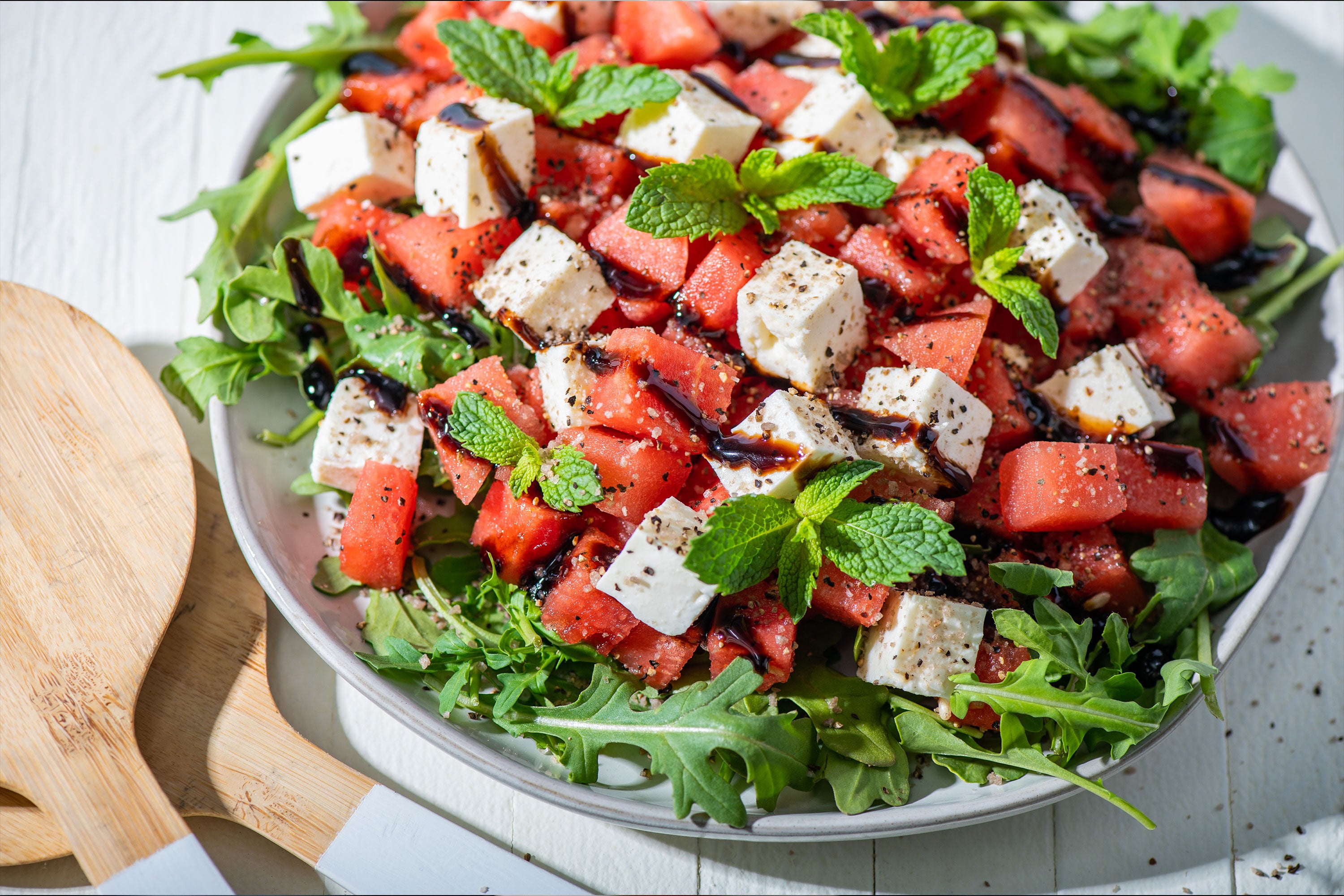 Watermelon and Feta Salad in bowl with two wooden utensils to the left