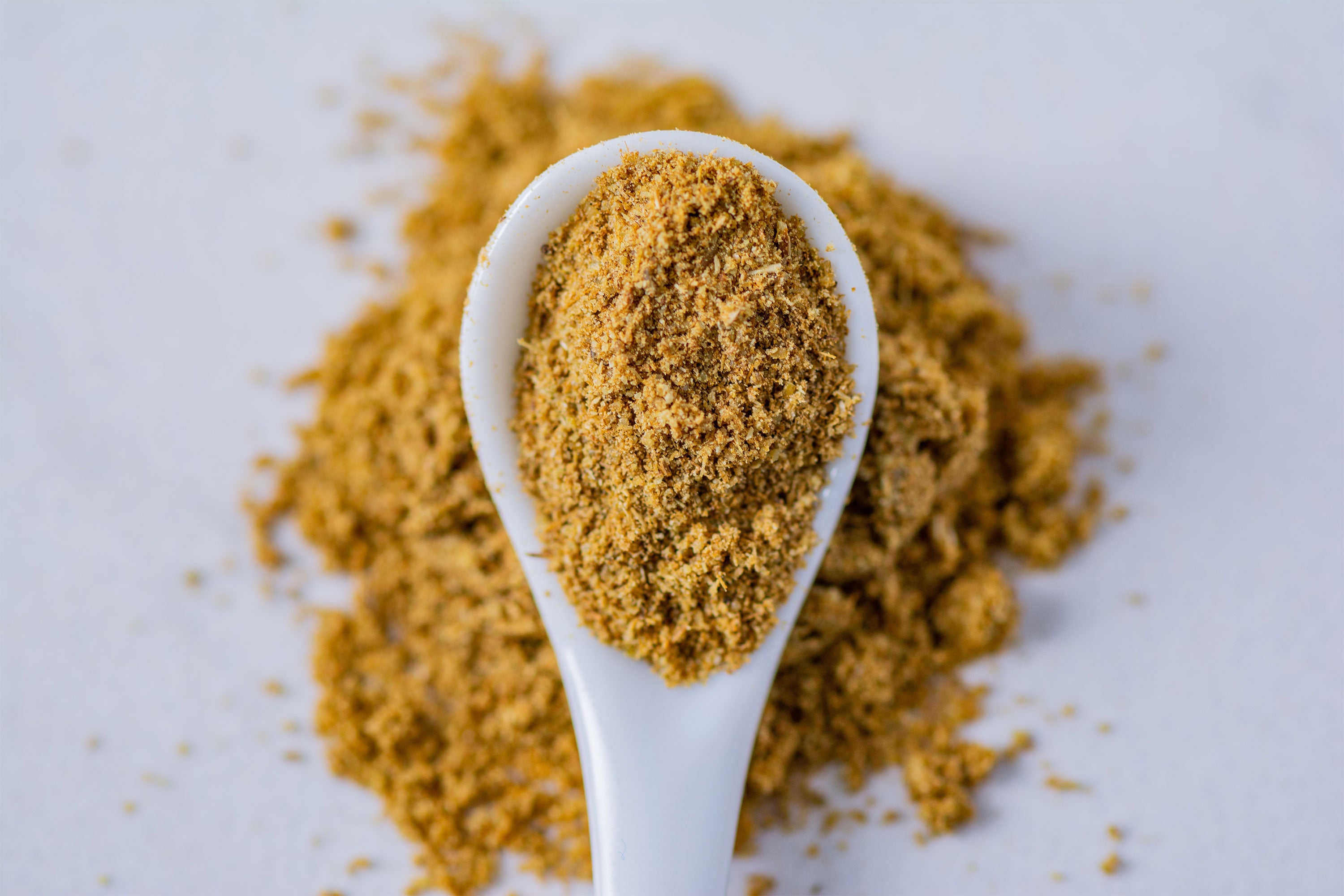 Spoon with ground cumin on neutral background