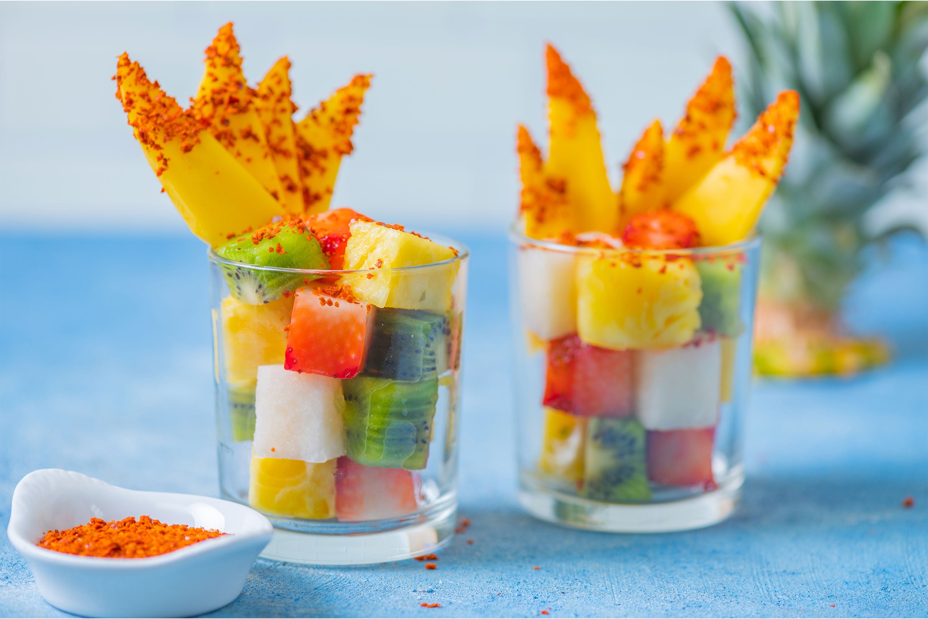 Two beachside fruit cups with chile powder and mango fan