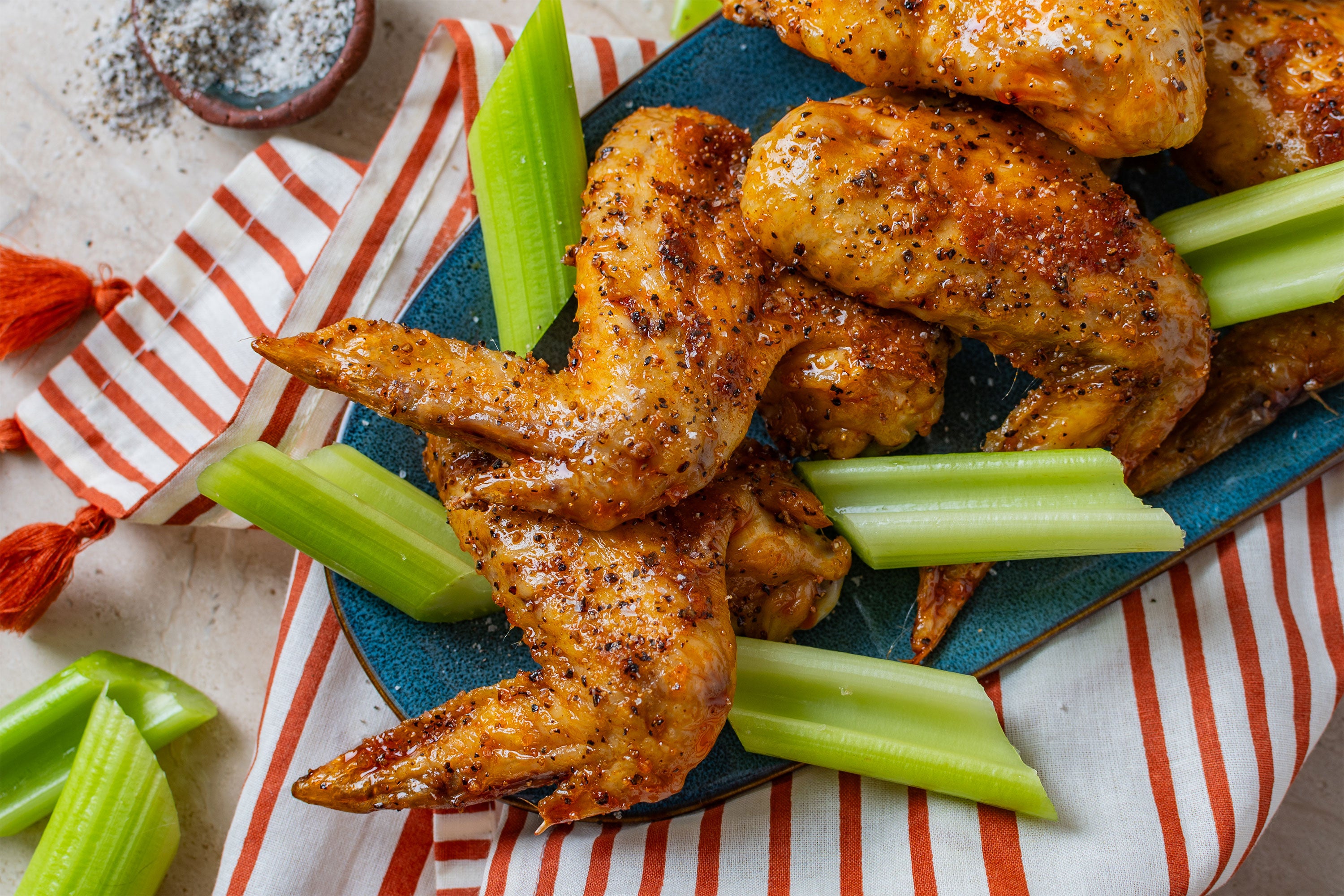 Pepper Chicken Wings with celery on a striped napkin