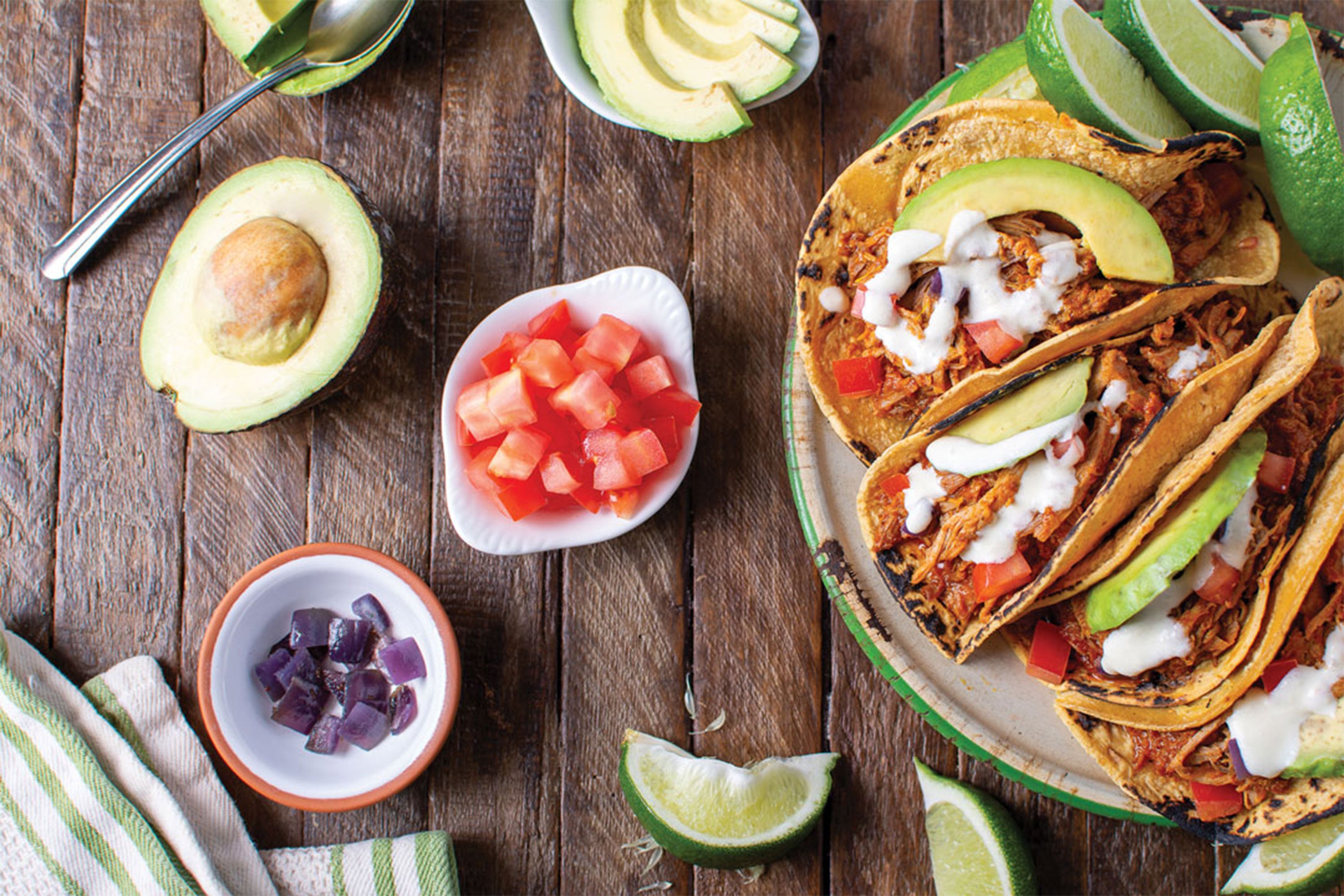 Cochinita Pebil tacos on right with assorted toppings on left