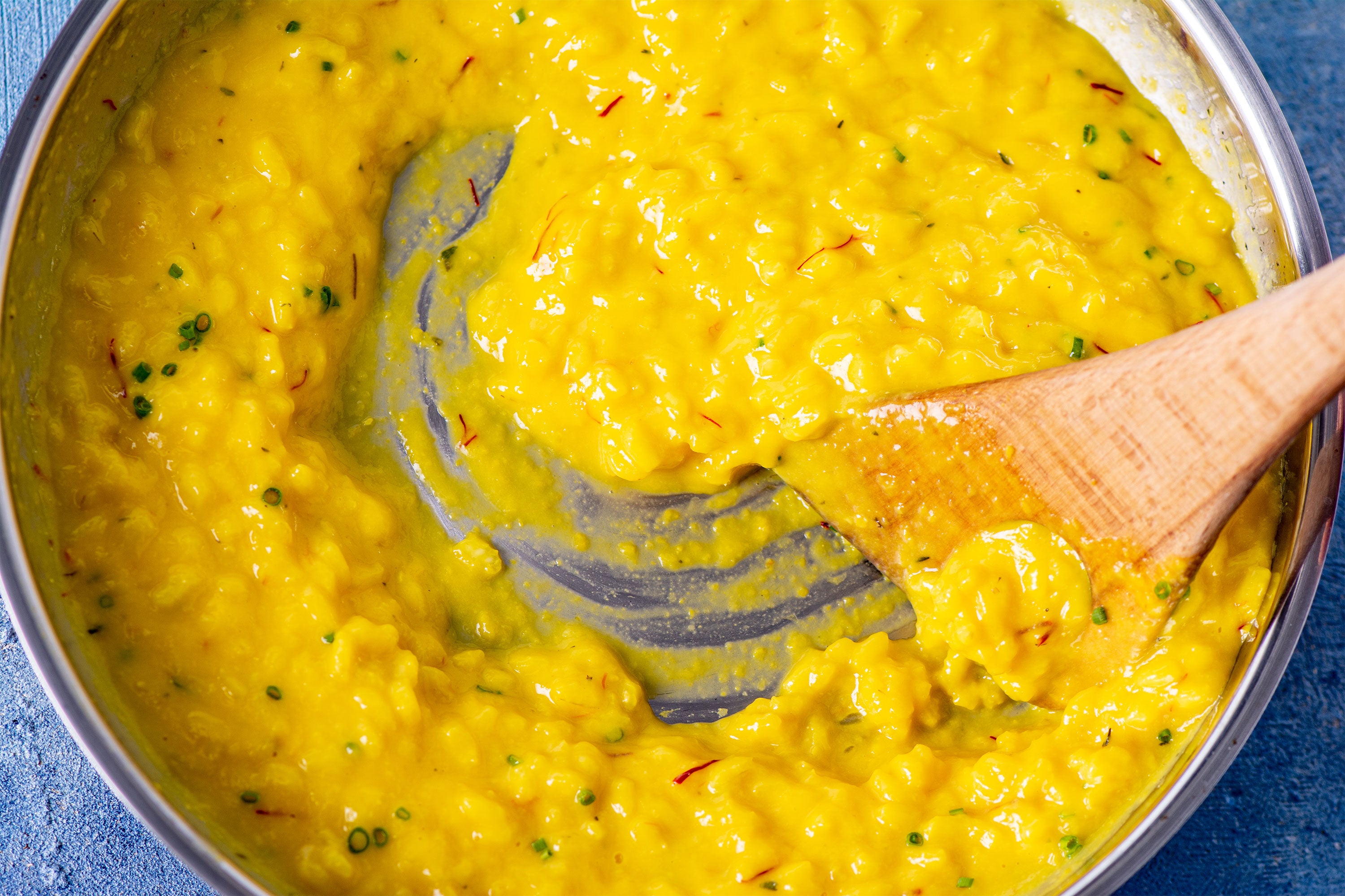 Saffron & Sweet Corn Risotto with a wooden spoon stirring