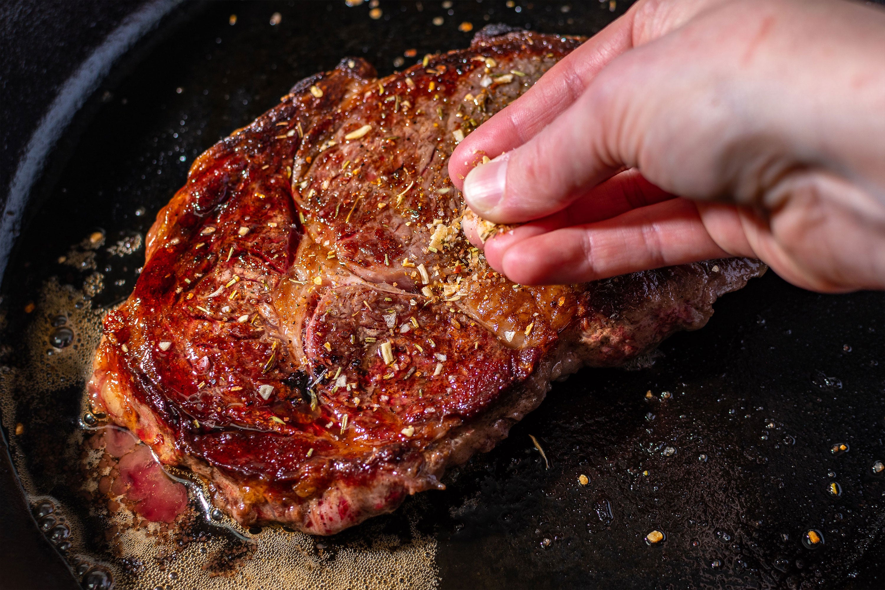 Sprinkling salt on a cooking steak