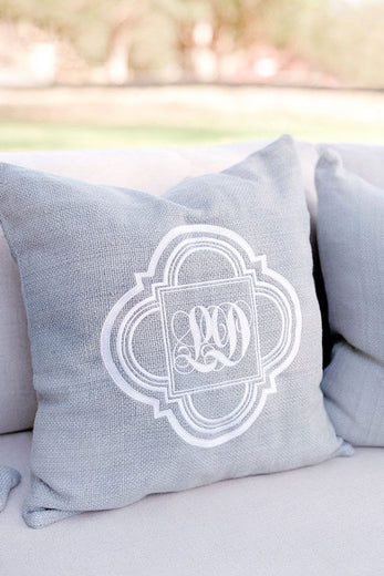 gray decorative pillow with an embroidered white wedding monogram