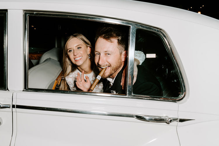 wedding couple in classic car groom holding cigar with monogram