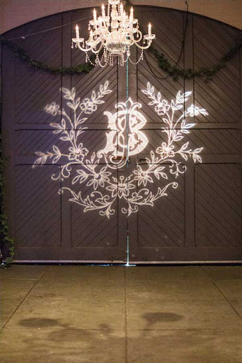 monogram projected with lighting on the doors of wedding reception
