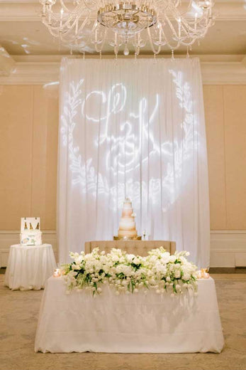 monogram lighting on wall behind cake table at a wedding reception