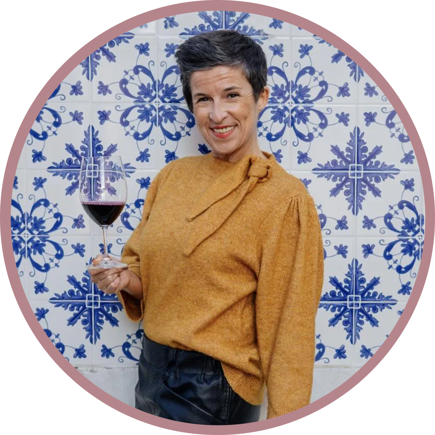 Portuguese sommelier Teresa Gomes smiling and holding a glass of wine, against a backdrop of traditional blue Portuguese tiles.