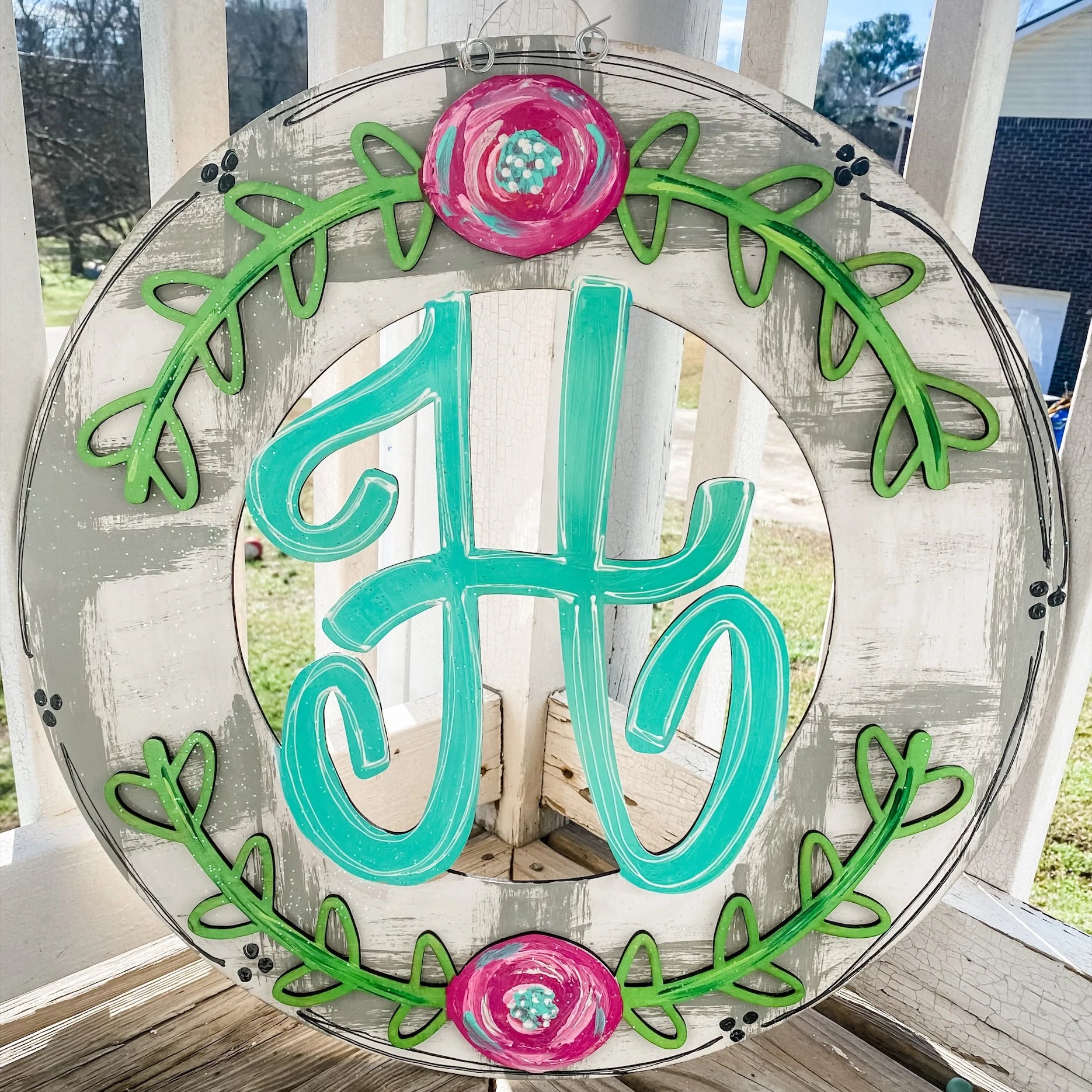 Circular spring-themed door hanger with family initial and flowers and vines around the edges