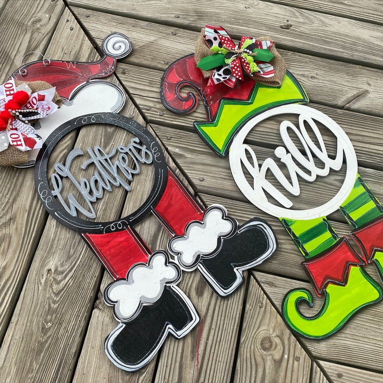 Two Christmas-themed door hangers in the shape of Santa and an elf