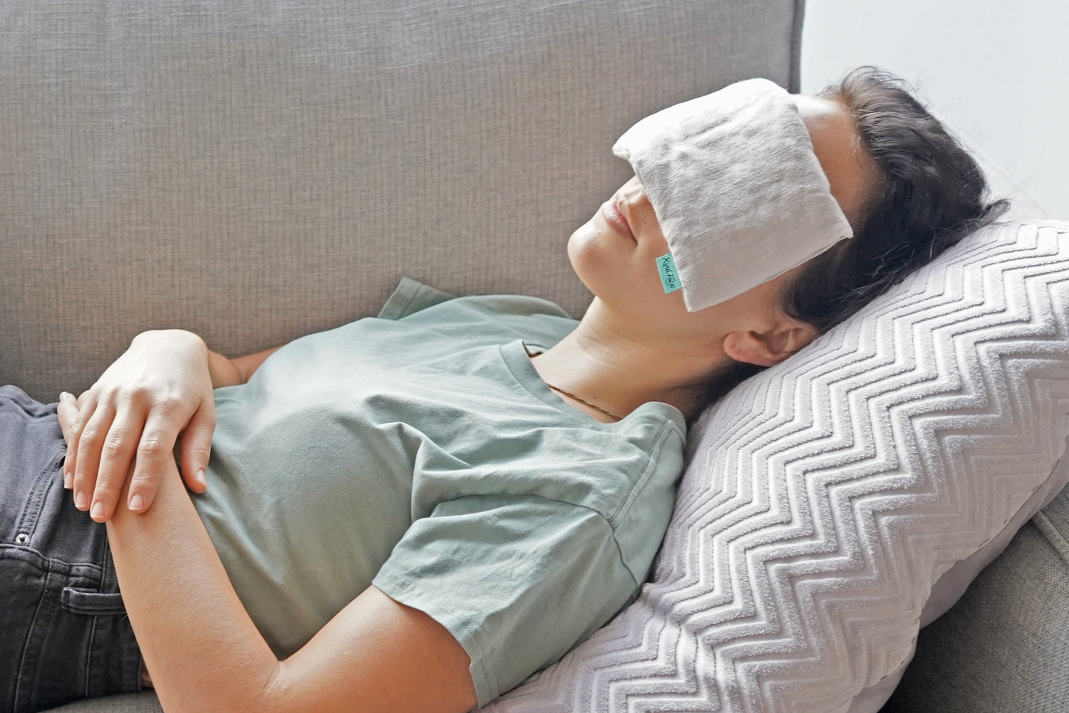 Picture of woman snoozing on the couch with Kind Face Weighted Eye Pillow