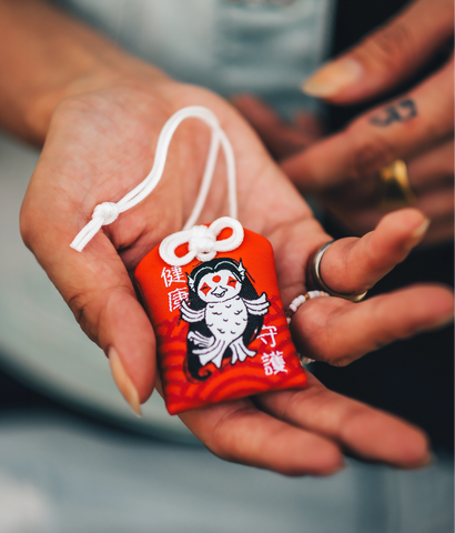 To own an Omamori, visit a shrine, choose one that speaks to you, keep it close, and show it respect by keeping it clean and offering prayers regularly