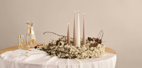Festive display of golden cone shapped candles in twigs, and moss: perfect christmas table display