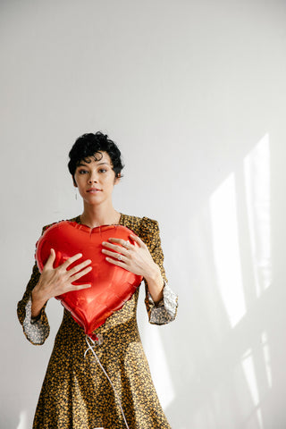 A woman holding a large red heart to symbolize love