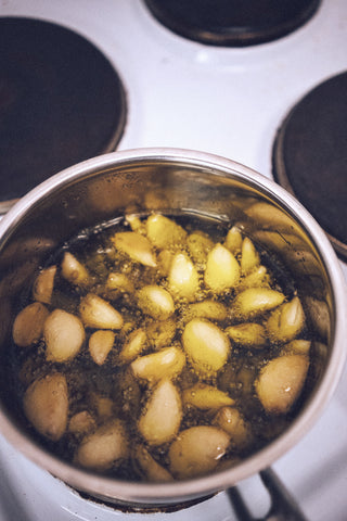 Garlic confit cooking in olive oil