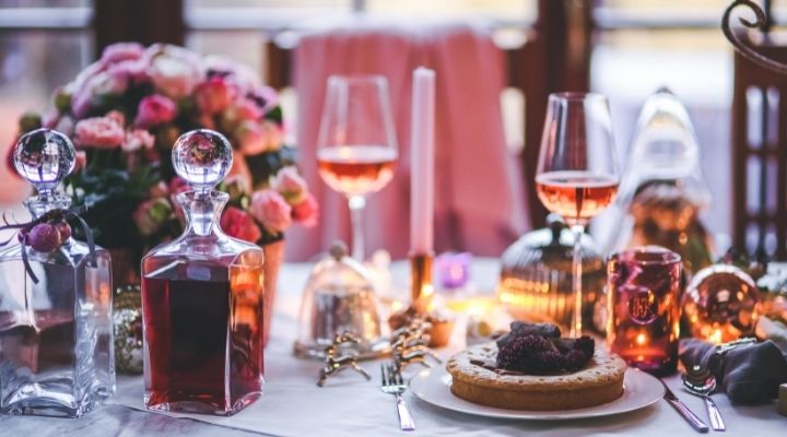 Dinner party scene with candles, wine glasses, decanter, and dessert