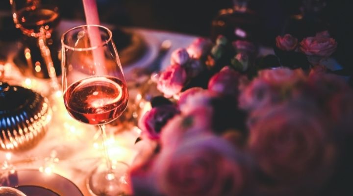 Wine glass half full, on an elegant dinner table with candle light