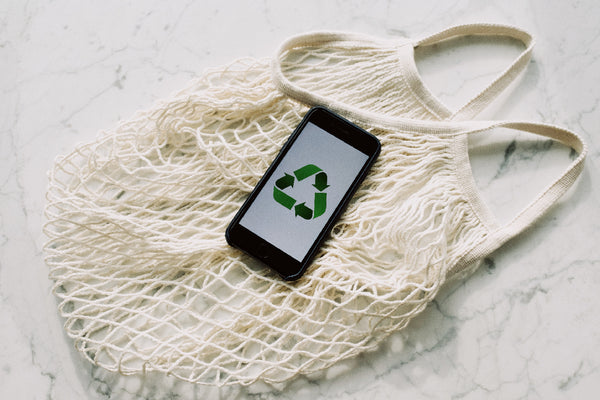 Eco-friendly bags and cell phones with recycling symbols on them