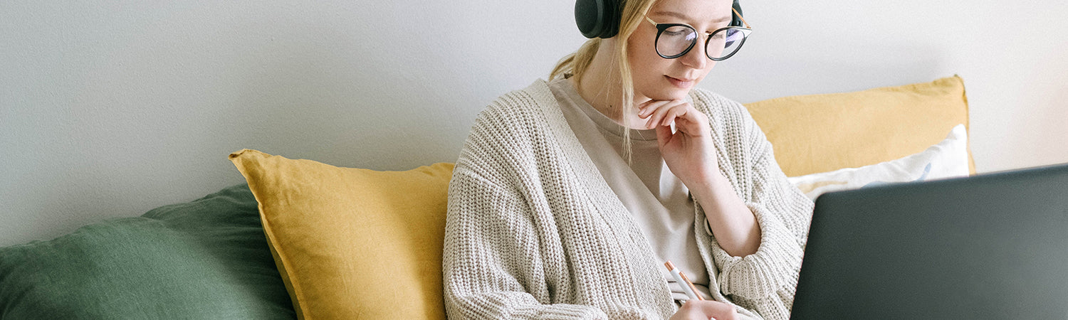 a woman with headphones with a tablet sitting on the sofa and thinking down