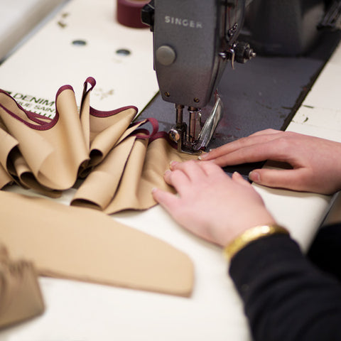 Des mains sur une machine à coudre à l'atelier Dao