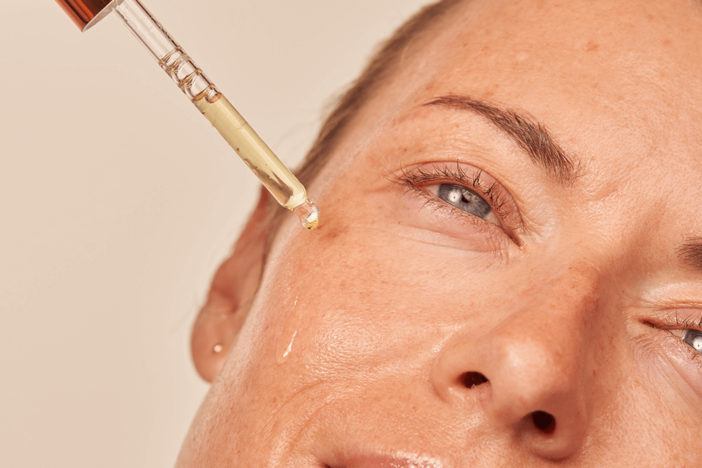 Woman applying Dr. Dennis Gross Vitamin C Lactic 15% Vitamin C Firm & Bright Serum to her face