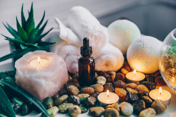 Bottle of essential oil surrounded by candles