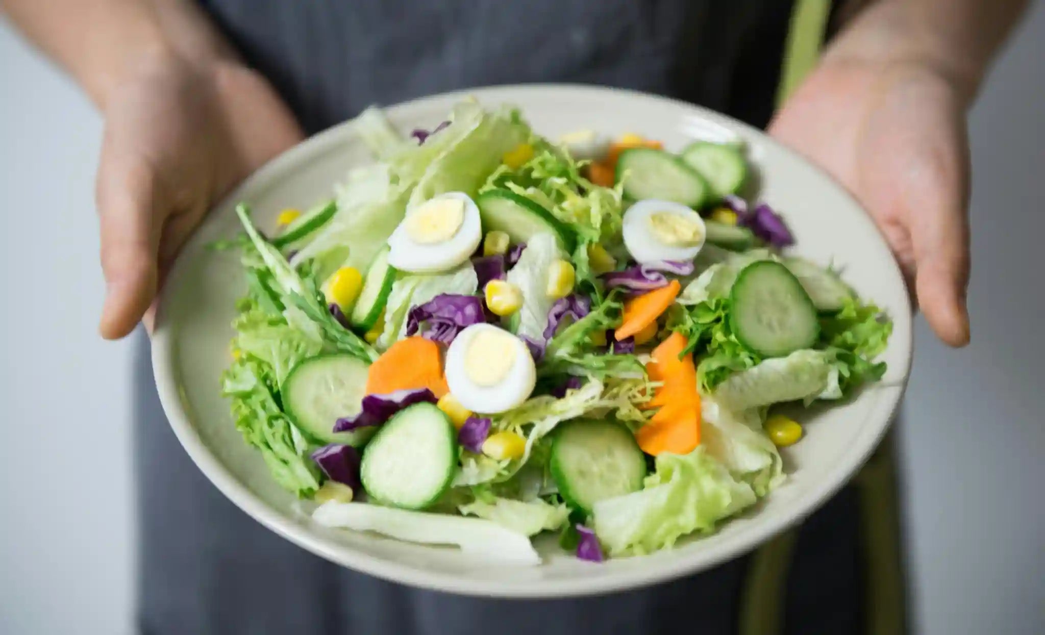 A fresh salad with leafy greens, cucumbers, carrots, eggs, and corn, to combat oxidative stress