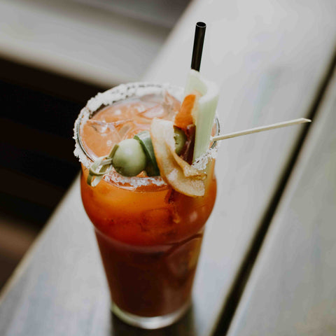 Bloody Mary with black straw on top of a table.