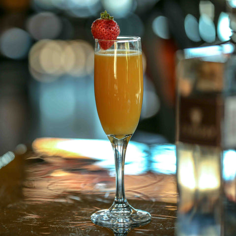 Mimosa cocktail on a flute glass with a strawberry garnish