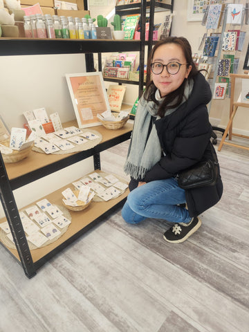 Smiling girl crouching beside polymer clay earring display