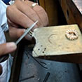 Image of a person working on a ring, depicting just the hands, ring, and tools