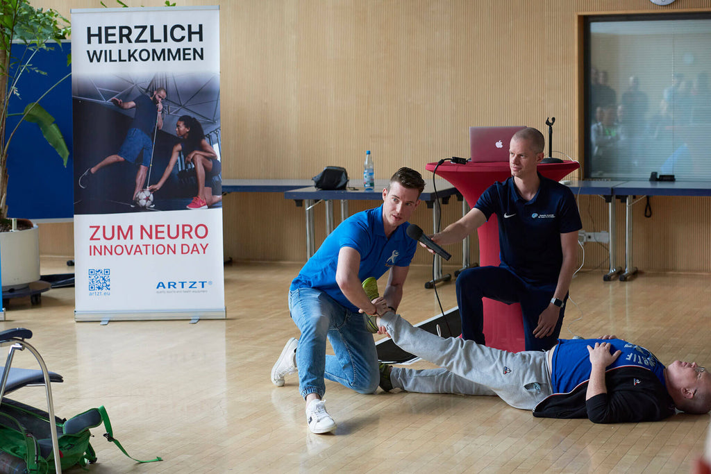 Le neuro-athlétiseur Kevin Grafen traite la jambe gauche d'un homme allongé sur le sol lors de la Journée de l'innovation neurologique 2022.