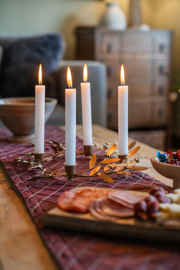 Hygge-inspired coffee table decor ideas with burgundy runner, Arthur Cameron Dolcoath candleholder, Eze mango wood serving board and Nîmes mango wood bowls.