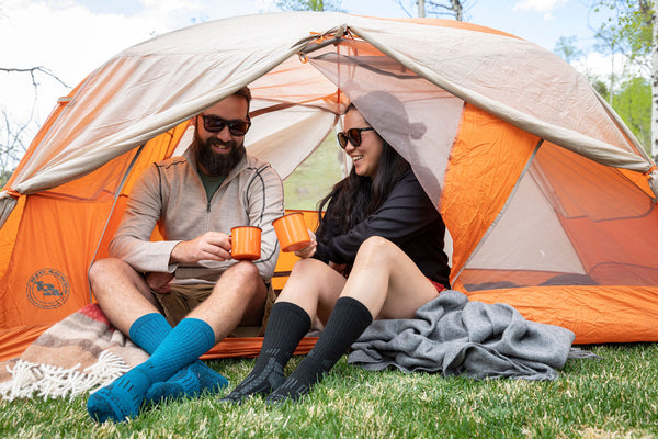 two people sitting in an orange tent with alpaca wool products on