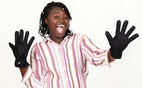black woman smiling big wearing pink shirt and alpaca gloves
