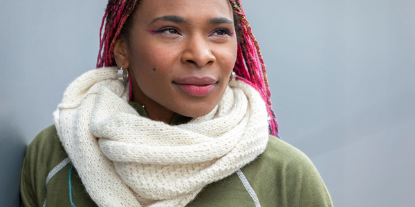 black woman looking into the distance wearing handmade white alpaca wool infinity scarf and green base layer