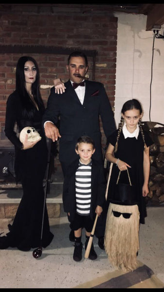 A family of four dressed in an Addams Family group Halloween costume.