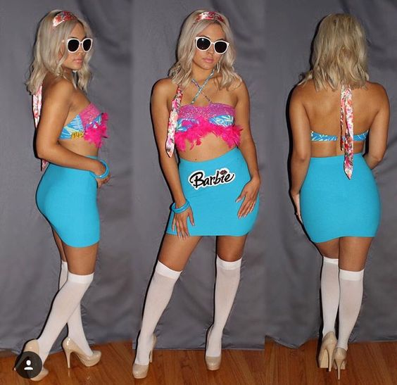 A woman wears a DIY Barbie Halloween costume with a blue skirt, patterned bikini top, and white sunglasses.