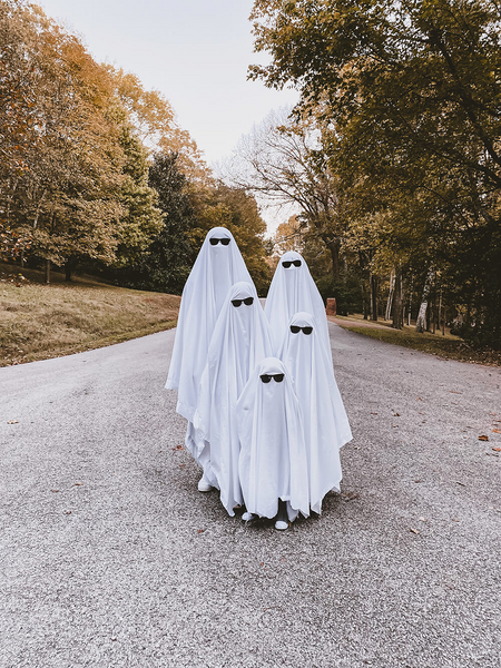 A group wearing bedsheet ghost Halloween costumes with sunglasses.