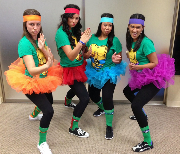 A group of women wearing Ninja Turtles t-shirts paired with color-coded tutu skirts and bandanas.