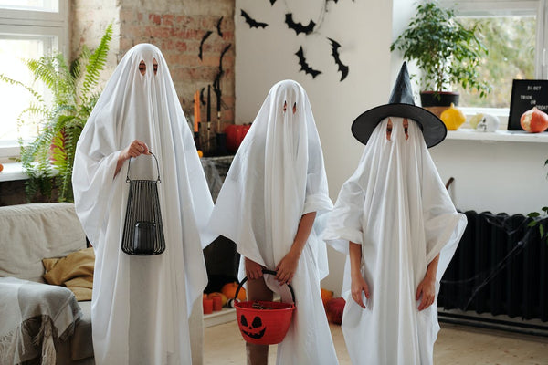 A family dressed in bedsheet ghost Halloween costumes.