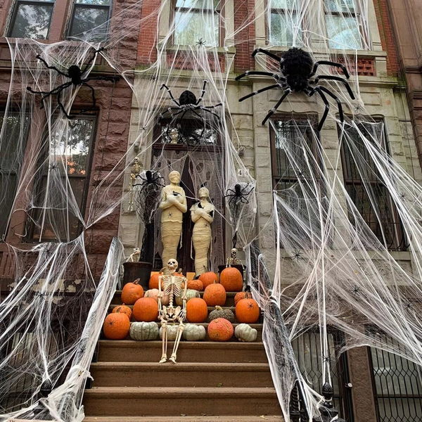 Giant spider web decorations draped over the front stoop of a home.
